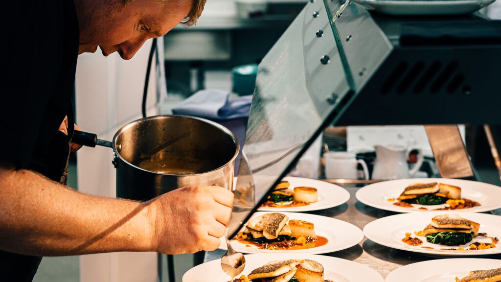 Bilden visar en person i ett restaurangkök. Restaurangmaskiner av hög kvalitet underlättar i restaurangkök och storkök.